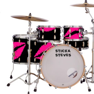 Puede incluir: Una batería negra con labios rosas impresos en las cabezas de los tambores. El bombo tiene el texto "STICKA STEVES" impreso en él.