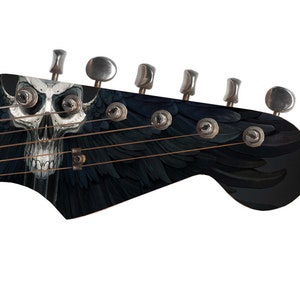 Pu&ograve; includere: Una paletta di chitarra elettrica nera con un design a forma di teschio e ali. La chitarra ha sei meccaniche e una finitura nera.