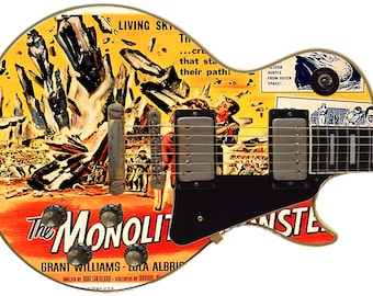 May include: A vintage electric guitar with a custom design featuring a movie poster for "The Monolith Monsters". The poster shows a scene of giant crystals falling from the sky, with people running away. The guitar has a black body and a white pickguard. The text on the poster reads "Living Sky...cru that sta their path!"