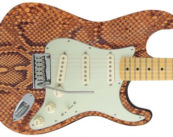 Può includere: Una chitarra elettrica marrone e beige con un motivo a pelle di serpente. La chitarra ha un battipenna bianco con tre manopole e un ponte cromato.