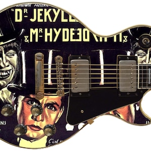 Puede incluir: Una guitarra eléctrica negra con un diseño personalizado que presenta un cartel de película vintage para "Dr. Jekyll y Mr. Hyde". El cartel presenta a dos hombres con sombreros de copa, uno con una sonrisa siniestra y el otro con una expresión más neutral. La guitarra tiene herrajes dorados y una placa protectora negra.