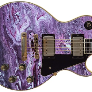 May include: Purple and white electric guitar with a marbled paint design. The guitar has gold hardware and a black pickguard.