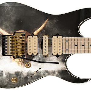 以下が含まれることがあります： ボディに頭蓋骨と角のデザインが施された黒いエレキギター。ギターは白のアウトラインと金色の金具で黒く仕上げられています。