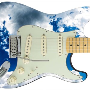 Op de afbeelding: Een blauwe en witte elektrische gitaar met een wolkendesign. De gitaar heeft een lichte houten hals en een witte pickguard.