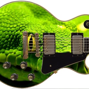 May include: A green electric guitar with a snake skin design. The guitar has a black pickguard and a gold-colored hardware. The snake's eye is visible on the body of the guitar.