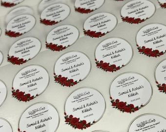 Könnte beinhalten: Ein Bogen runder, weißer Aufkleber mit roten Rosen und goldenen Verzierungen. Die Aufkleber zeigen den Text "Samiul & Aishah's Nikkah" und das Datum "15.05.2022".