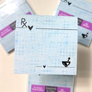 May include: Light blue 3x3 inch Post-it notes with a diamond pattern. Each note features a black Rx symbol, a heart, a line, and a mortar and pestle design. The notes are from Savannah & T-Rex.