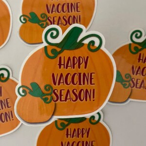 May include: A set of four orange pumpkin stickers with green stems and leaves. The stickers have the text "Happy Vaccine Season!" in red lettering.