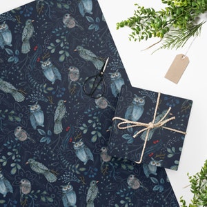 May include: A dark blue wrapping paper with a repeating pattern of owls, birds, and leaves. The owls are gray and white with yellow eyes. The birds are blue and white with yellow beaks. The leaves are green and white.