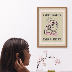 May include: A green and brown poster with a cartoon illustration of a princess wearing a crown and a pink dress. The text on the poster reads "I don't have to earn rest."