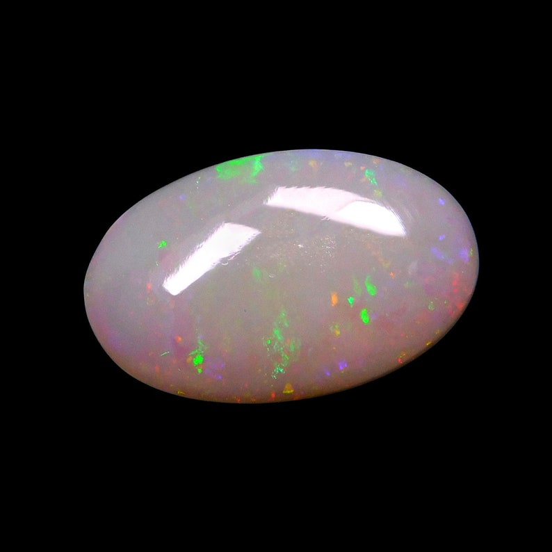 May include: A white opal gemstone with a smooth, oval shape. The opal has a subtle iridescent sheen with hints of green, red, and purple.