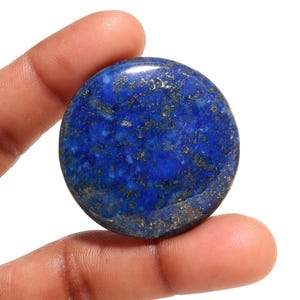 May include: A round, polished lapis lazuli stone with a deep blue color and flecks of gold pyrite.
