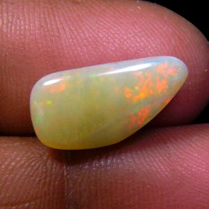 Peut inclure: Une pierre précieuse d'opale de couleur vert clair et orange en forme de larme.