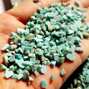 May include: A collection of small, irregular turquoise stone chips in varying shades of light blue and green. These tumbled mineral fragments feature matte textures and jagged edges, showcasing natural colour variations throughout the pile.