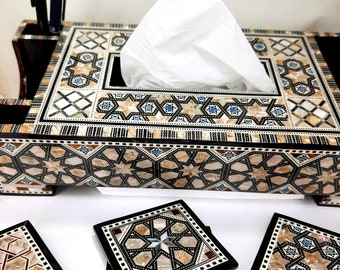 May include: An ornate tissue box and coasters set. The tissue box features a geometric design with mother-of-pearl inlay, and a stack of matching coasters are in the foreground. The set is accented with black trim and includes a pen holder.