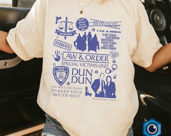 May include: A white t-shirt with a blue graphic print of the Law & Order: Special Victims Unit logo. The graphic includes the show's title, the unit's name, and the text "Dun Dun" with a police badge and handcuffs. The text "You have the right to keep your mouth shut" is also included.