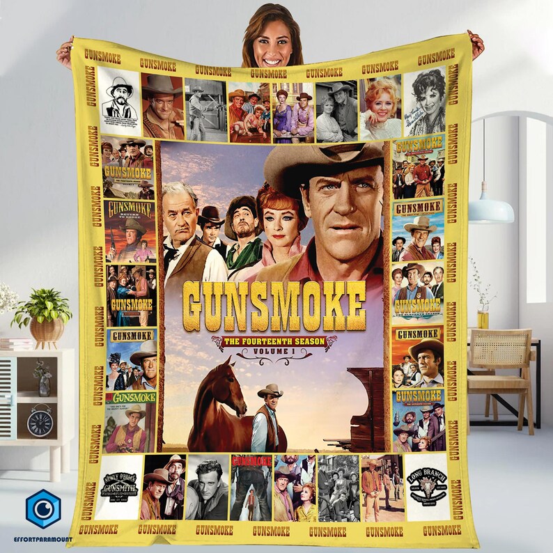 Może przedstawiać: Ż&oacute;łty koc Gunsmoke z wizerunkami obsady i logo serialu. Na kocu widnieje napis "Gunsmoke The Fourteenth Season Volume I" oraz r&oacute;żne zdjęcia obsady. Koc jest trzymany przez osobę.