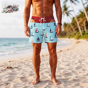 Può includere: Costume da bagno azzurro con un motivo ripetuto di barche a vela con vele bianche e scafi scuri. La fascia in vita è in tessuto rosso scuro a contrasto con pois bianchi e include un cordino bianco per la regolazione.