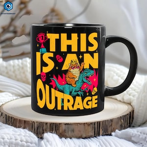 May include: Black ceramic mug with a humorous graphic. The design features a cat wearing sunglasses and a crown, riding a dinosaur, with the words "THIS IS AN OUTRAGE" in yellow. The mug has a black handle.