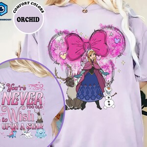 A t-shirt with a cartoon image of a girl surrounded by various characters, including a reindeer and a snowman. The text on the t-shirt says "You're never too old to wish upon a stair".