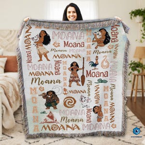 A woman is holding up a large blanket with the Moana characters from the Disney animated film prominently displayed on it.