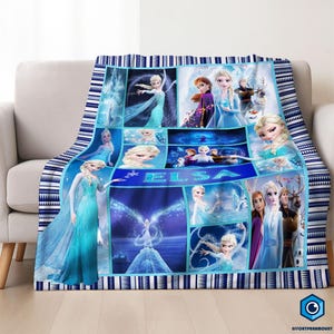 May include: A blue and white patterned throw blanket featuring images of Elsa from the movie Frozen. The blanket has a collage design with the name "ELSA" in the center and a blue and white striped border.