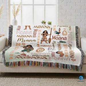 a cozy couch with a colorful throw blanket that has the word "Moana" printed on it. The blanket is adorned with various Moana characters and designs, creating a vibrant and playful atmosphere.