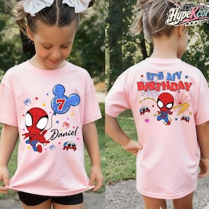 May include: Pink t-shirt featuring a cartoon Spider-Man design. The front of the shirt has a Spider-Man graphic, a balloon with the number 7, and the name "Daniel". The back of the shirt says "It's My Birthday" with a Spider-Man graphic.