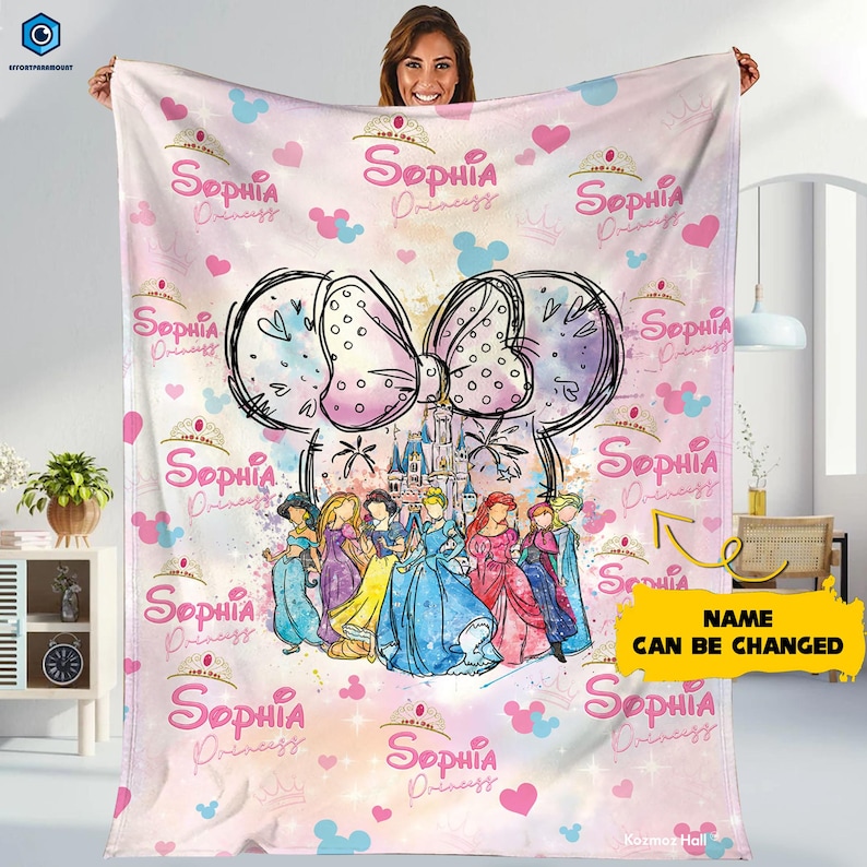 Puede incluir: Una manta rosa con un gran dise&ntilde;o de lazo, un castillo e ilustraciones de princesas. La manta tiene el nombre "Sophia Princess" repetido, junto con corazones y siluetas de Mickey Mouse. Tambi&eacute;n es visible el texto "NAME CAN BE CHANGED".