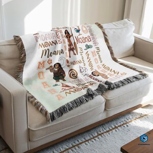 a cozy couch with a colorful throw blanket on it. The blanket is decorated with various Disney characters and the word "Moana" written on it.