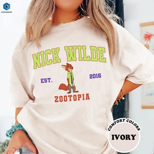 A person wearing a white t-shirt with a graphic of a cartoon character and text printed on it.