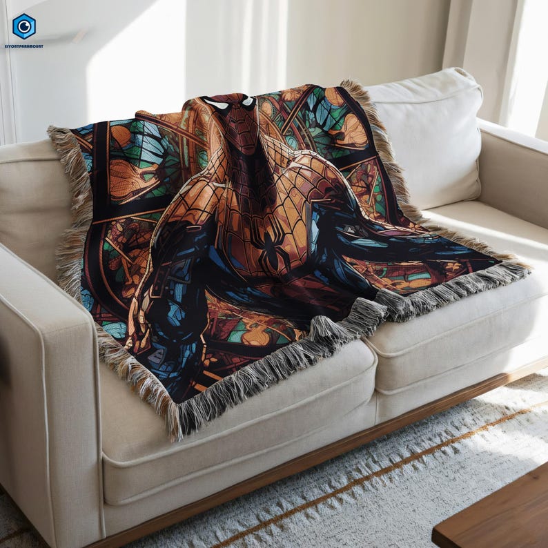A colorful, patterned blanket featuring a Spiderman character is draped over a white couch.