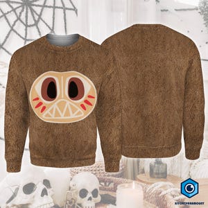 a brown sweater with a large, cartoonish face design on the front.
