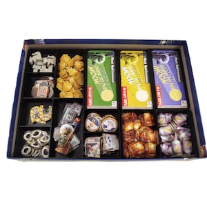 May include: A board game box with various game components organized in compartments. The box contains game cards, tokens, and booklets titled "Rocket Rats Guide to the Moon" in green, yellow, and purple. The game pieces are in various shapes and colors.