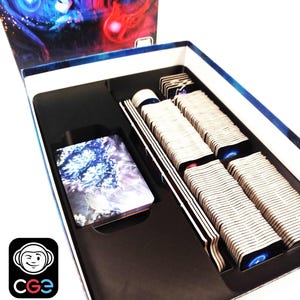 May include: A board game box with a colorful lid featuring abstract art. Inside, the box contains stacks of cards, game pieces, and a deck of cards with a blue and white design. The CGe logo is visible in the lower left corner.