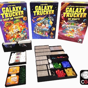 Peut inclure: Trois boîtes de jeu de société Galaxy Trucker, intitulées "Keep on Trucking" et "Do What?!", sont présentées. Les boîtes sont violettes, bleues et rouges, avec des illustrations colorées de vaisseaux spatiaux et d'astronautes. Les composants du jeu sont rangés dans des plateaux noirs.
