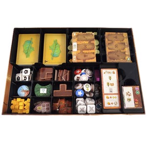 Op de afbeelding: Een zwarte bordspellen organizer met verschillende compartimenten gevuld met spelonderdelen. Inclusief kaarten met bladillustraties, dobbelstenen, houten blokken, tokens en spelborden. De organizer is ontworpen om bordspelstukken in op te bergen en te organiseren.