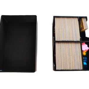 Puede incluir: Un organizador de juegos negro con una tapa separada. El organizador está dividido en compartimentos que contienen pilas de cartas y piezas de juego coloridas. Las cartas tienen una superficie marrón claro con líneas azules.