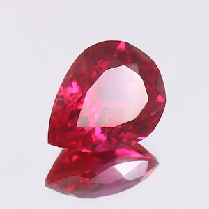 May include: A deep red pear-shaped gemstone with a faceted cut.