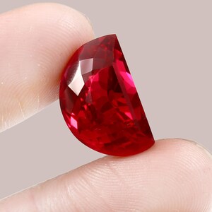 Könnte beinhalten: Ein großer, tief roter, facettierter Edelstein mit einer abgerundeten Halbmondform.