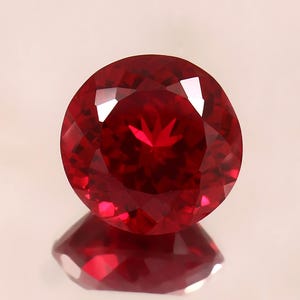 Può includere: Una pietra preziosa di colore rosso intenso con taglio rotondo e superficie sfaccettata.