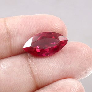 May include: A deep red marquise cut gemstone with a brilliant shine.