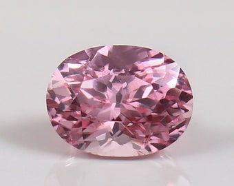 May include: A pink oval gemstone with a faceted cut. The gemstone is set against a white background.