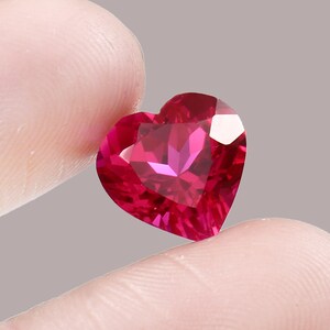 May include: A heart-shaped ruby gemstone with a deep red color and a faceted cut.