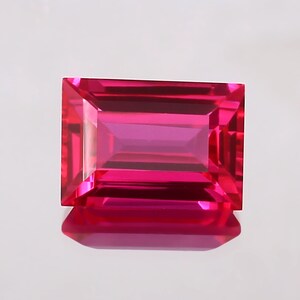 May include: A vibrant pink rectangular gemstone with a faceted cut.
