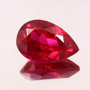 Peut inclure: Une pierre précieuse de rubis de forme poire avec une couleur rouge foncé. La pierre précieuse est facetée et présente un haut degré de brillance.