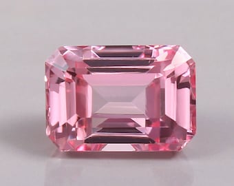 May include: A pink emerald cut gemstone with a high polish.