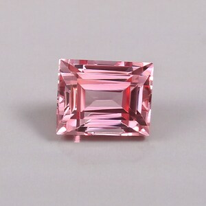 May include: A pink rectangular gemstone with a faceted cut.