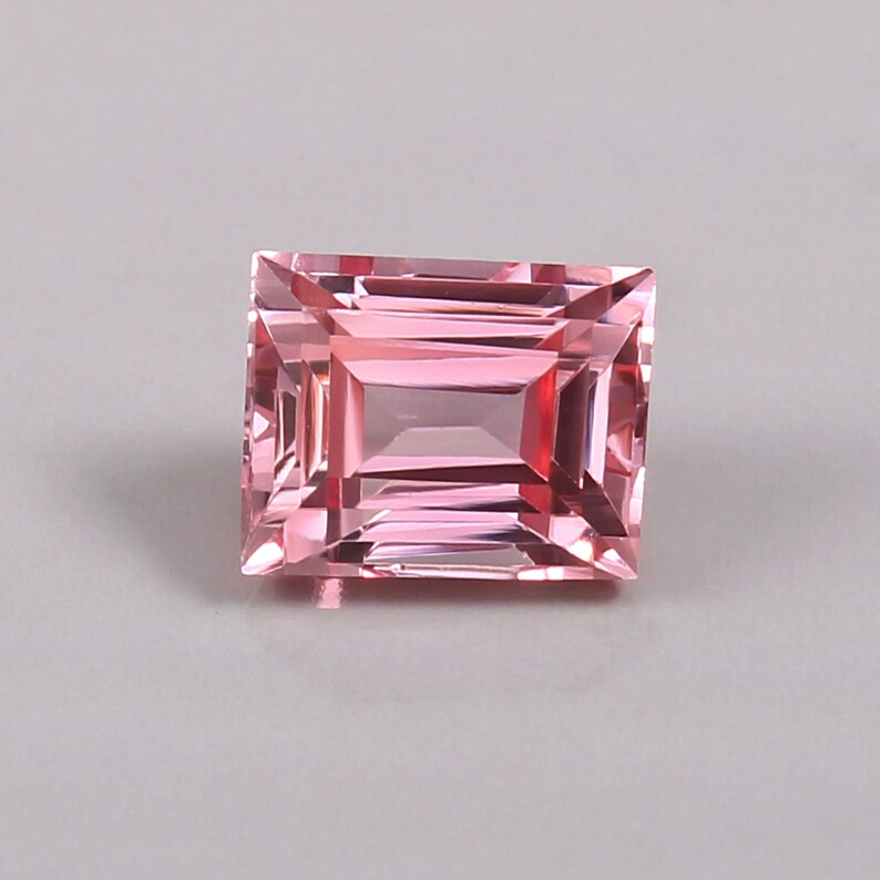 May include: A pink rectangular gemstone with a faceted cut.