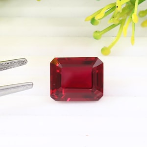 Könnte beinhalten: Ein tief roter Smaragdschliff-Edelstein mit hohem Glanz.